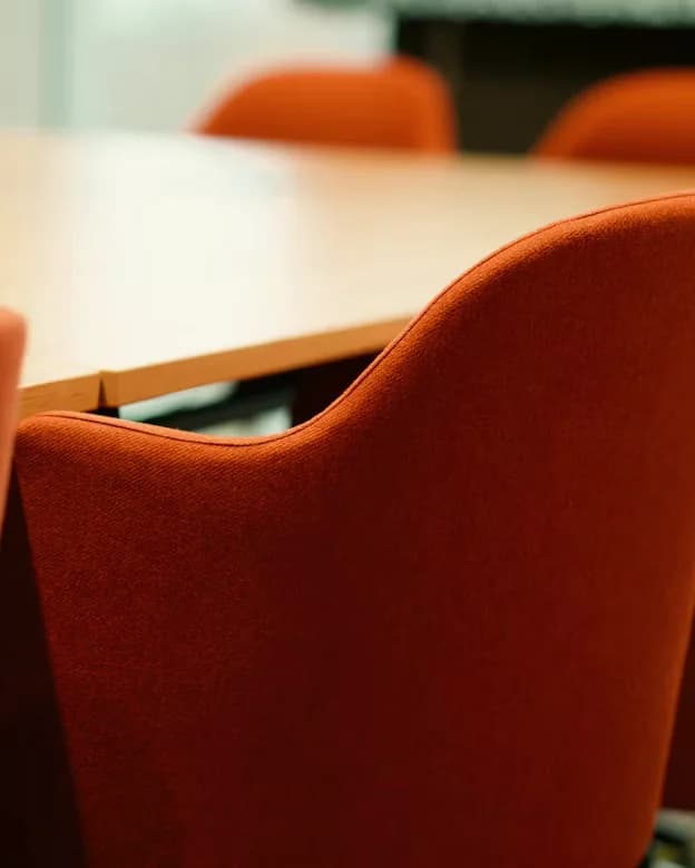 An empty boardroom lined with orange chairs