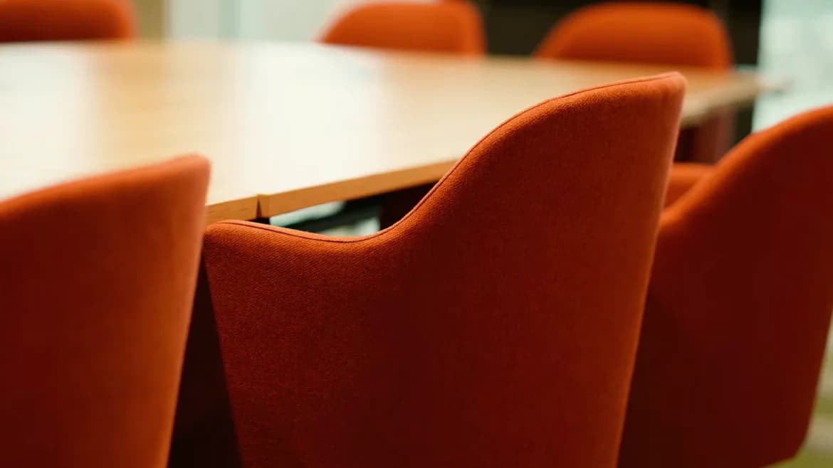 An empty boardroom lined with orange chairs